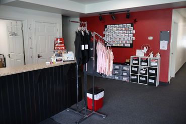 Dance studio reception with costumes and display board.
