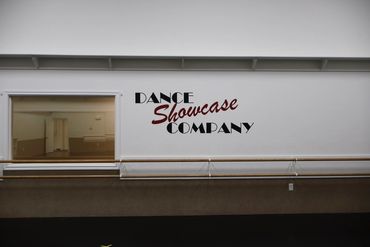 Dance studio wall with "Dance Showcase Company" text and ballet barres.