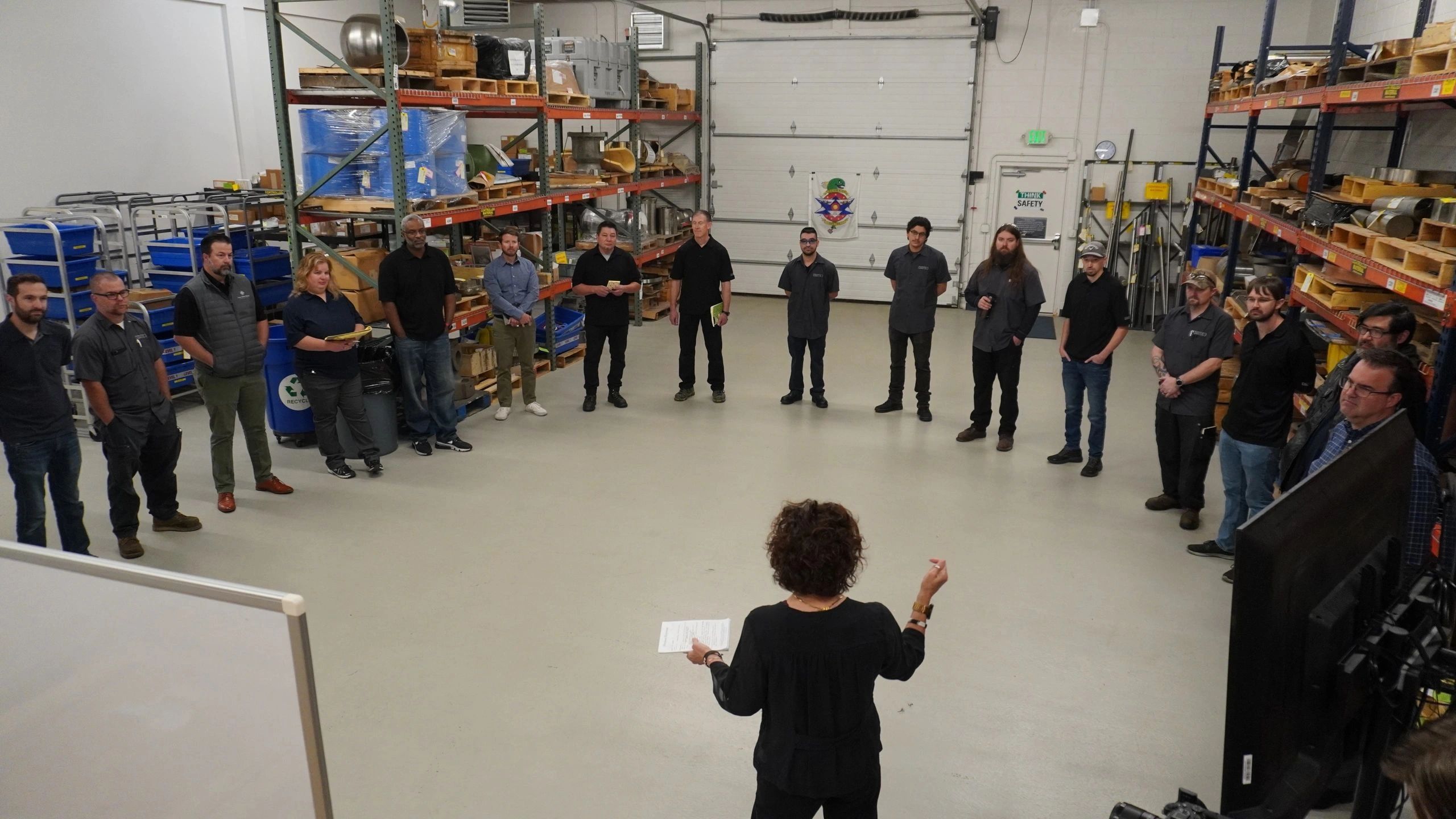 Group of people attending a meeting in a warehouse.