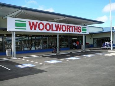Entrance of a Woolworths supermarket with empty parking spots.