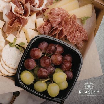 Charcuterie board with meats, cheeses, grapes, and crackers.