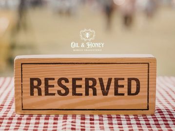 Wooden reserved sign on checkered tablecloth at outdoor event.