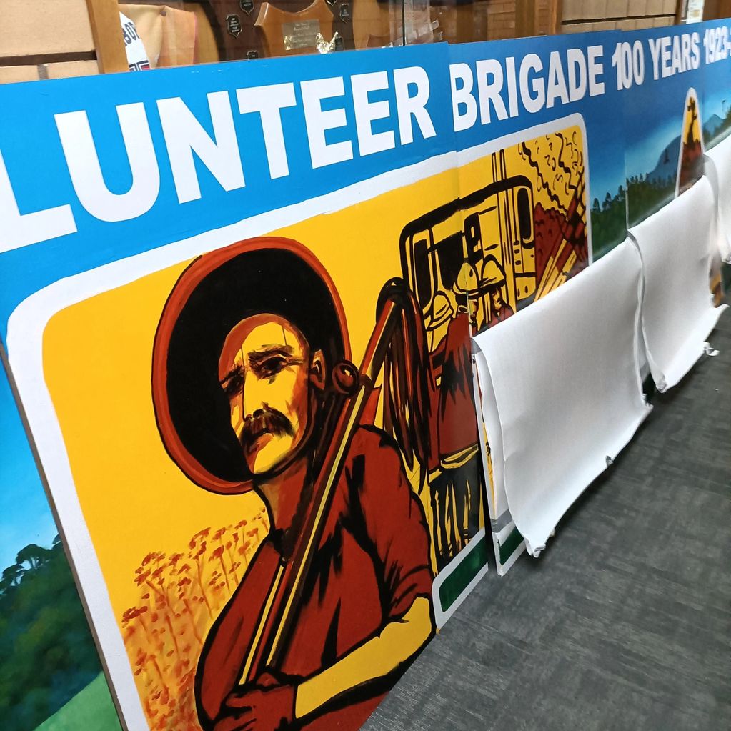Mural depicting a historical figure with a musket, part of a Volunteer Brigade display.