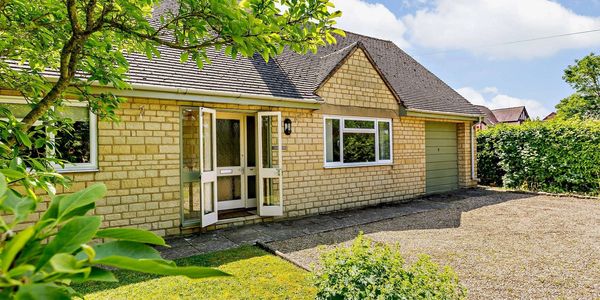 A charming stone house with an open front door and a green garage door.