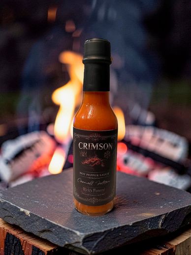 Bottle of Crimson hot pepper sauce in front of flames.