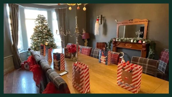Christmas-themed dining room with gift bags and a decorated tree.