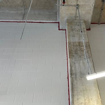 Industrial ceiling with exposed piping and concrete column.