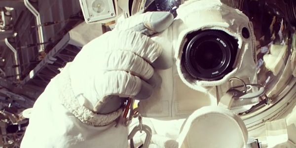 Astronaut in space suit taking a photo with a camera attached to the helmet.