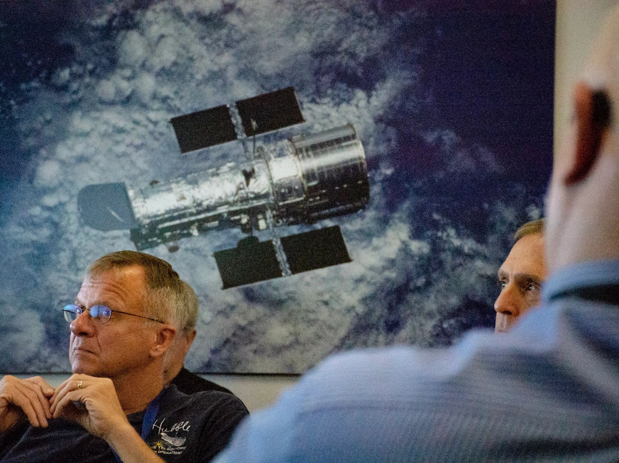 Two men in front of a Hubble Space Telescope image.