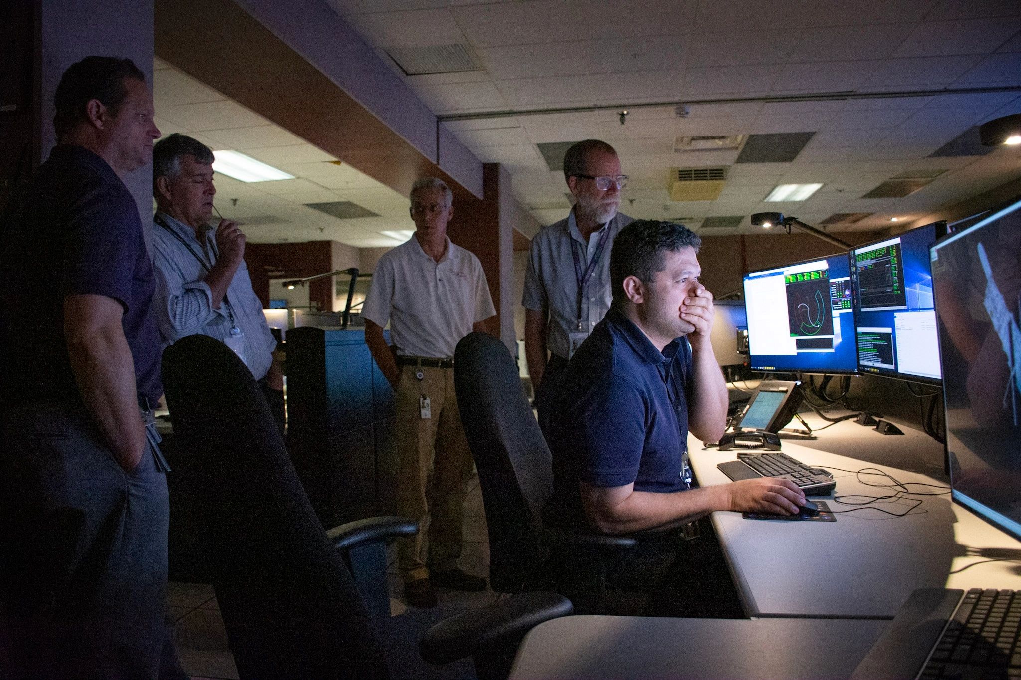 A group of men monitoring multiple computer screens.
