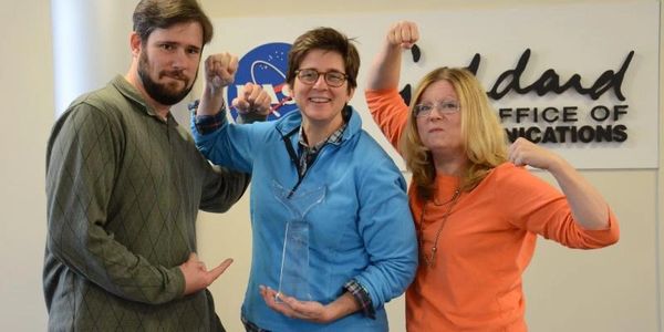 Three people posing with a trophy, showing strength and pride.