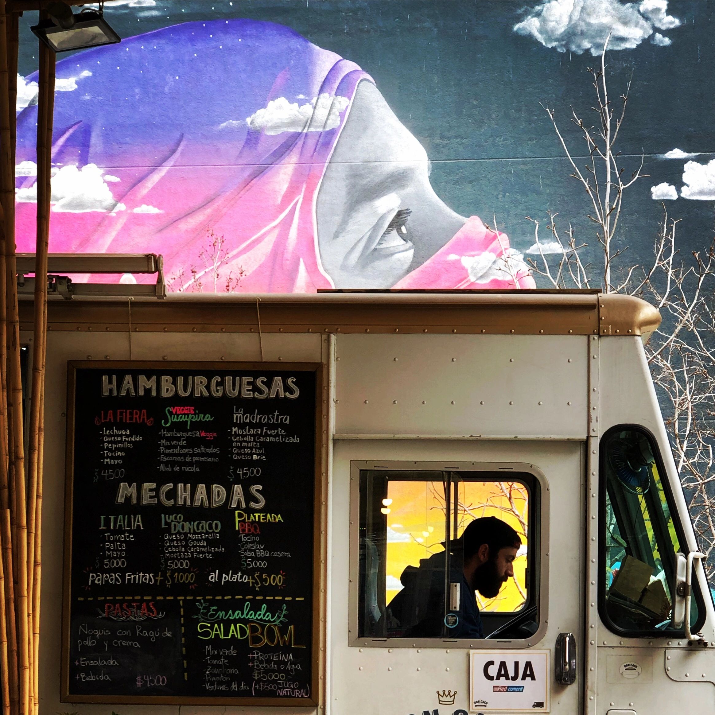 Colorful mural of a woman with a hijab on a food truck wall.