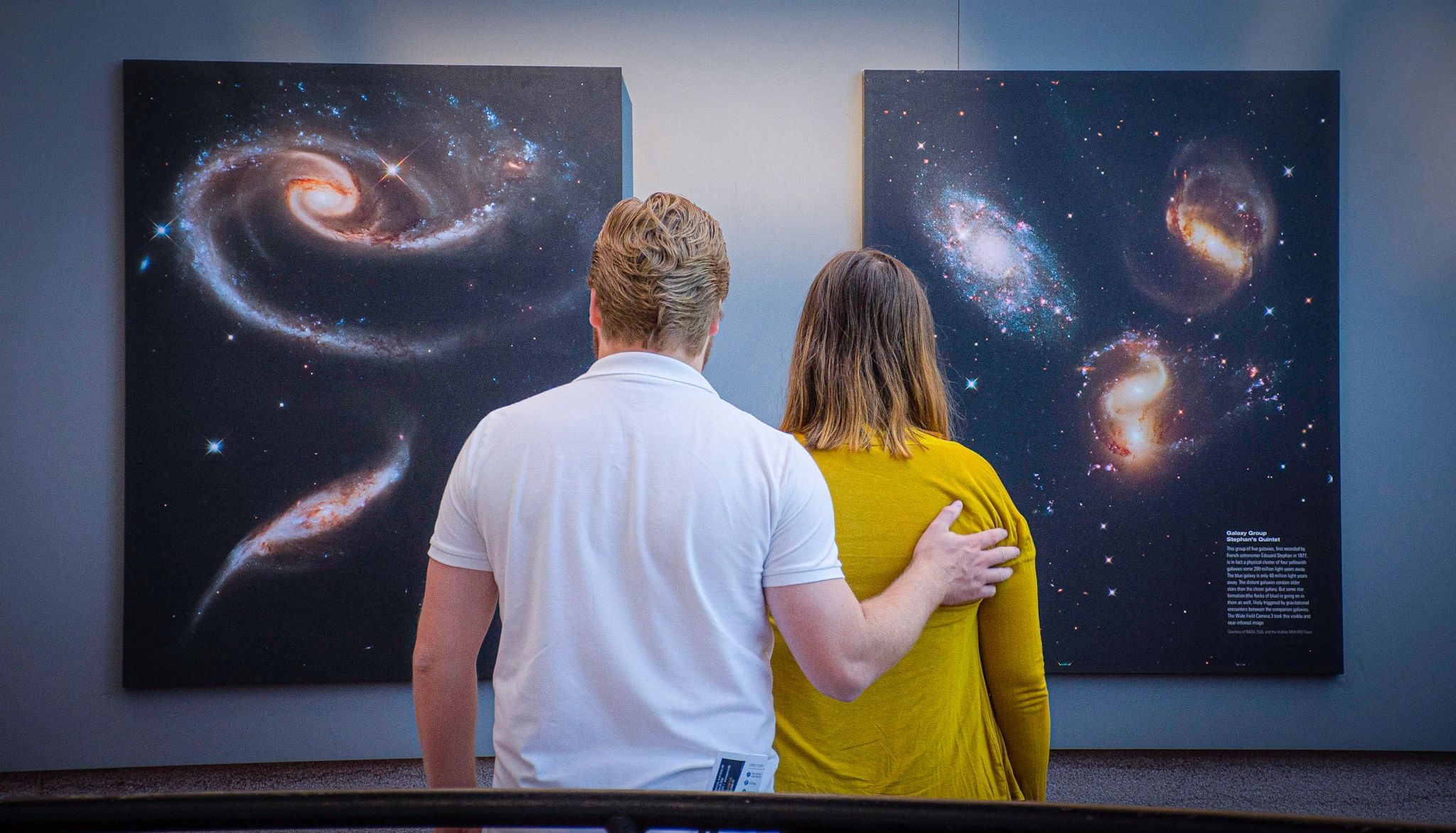 Couple admiring galaxy paintings in an art exhibit.