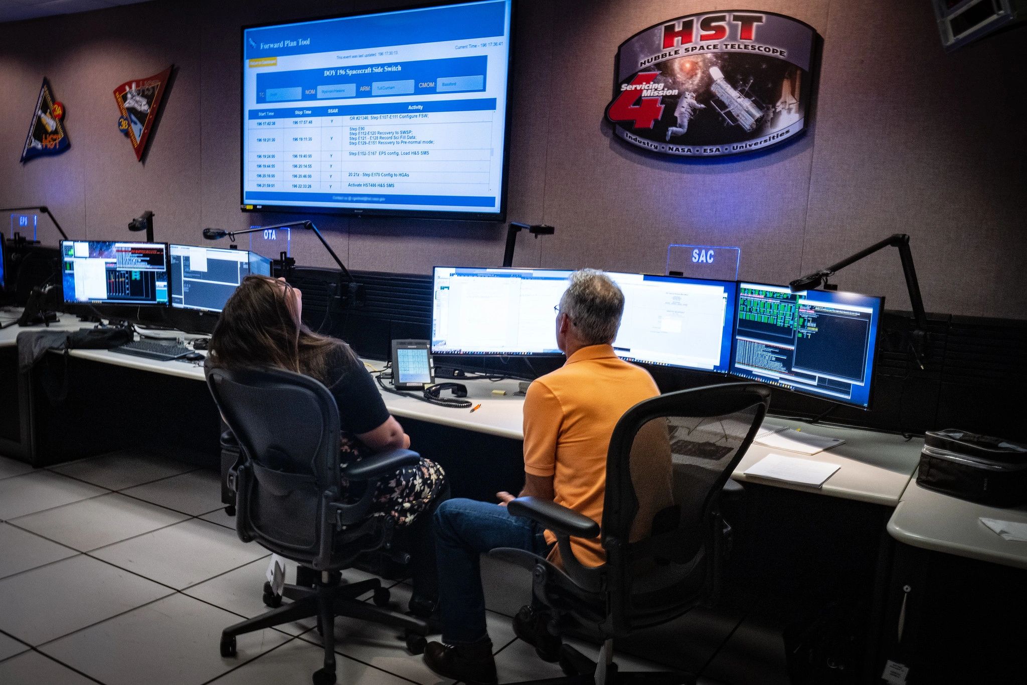 Two people working in a Hubble Space Telescope control room.