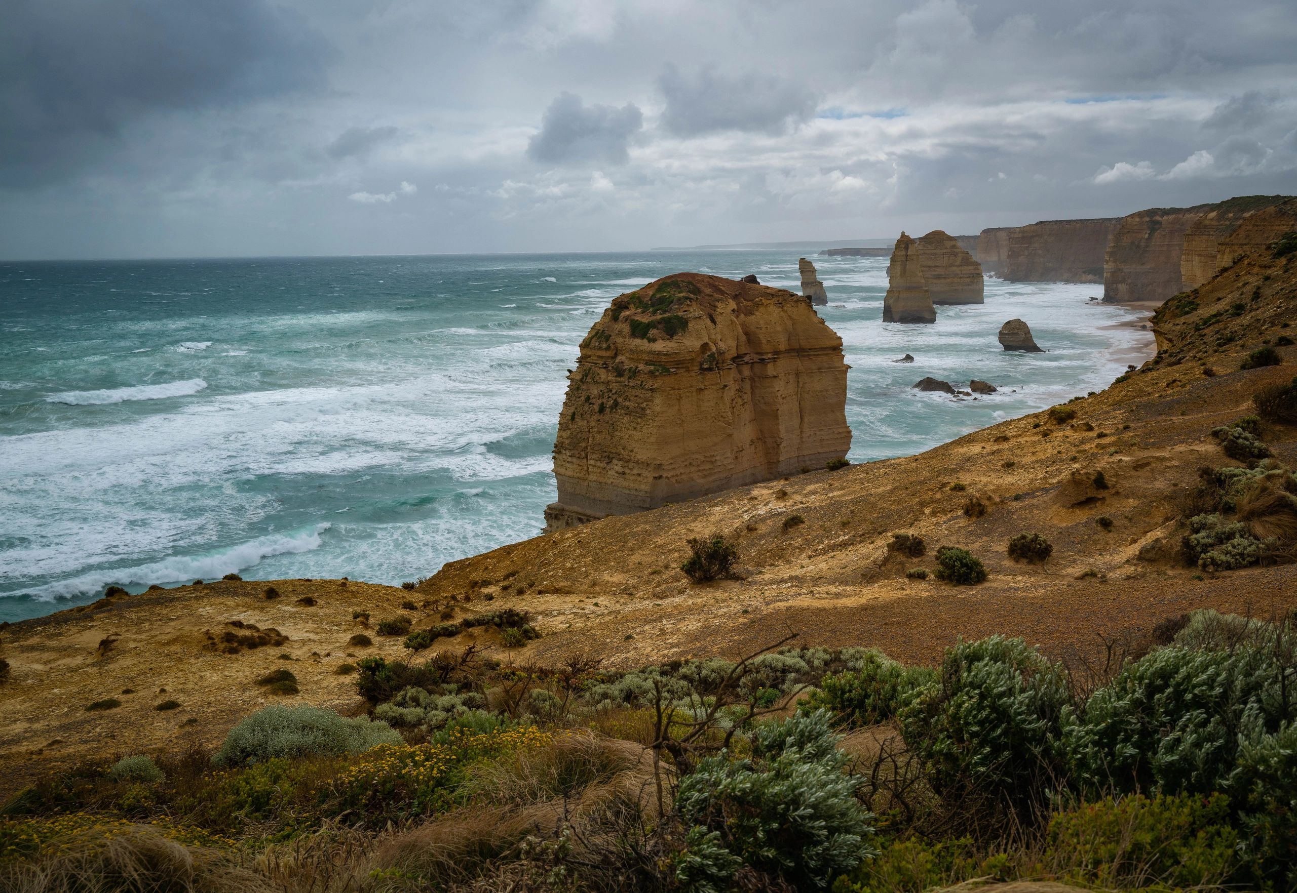 Rock formations along a rugged coastline under a cloudy sky.