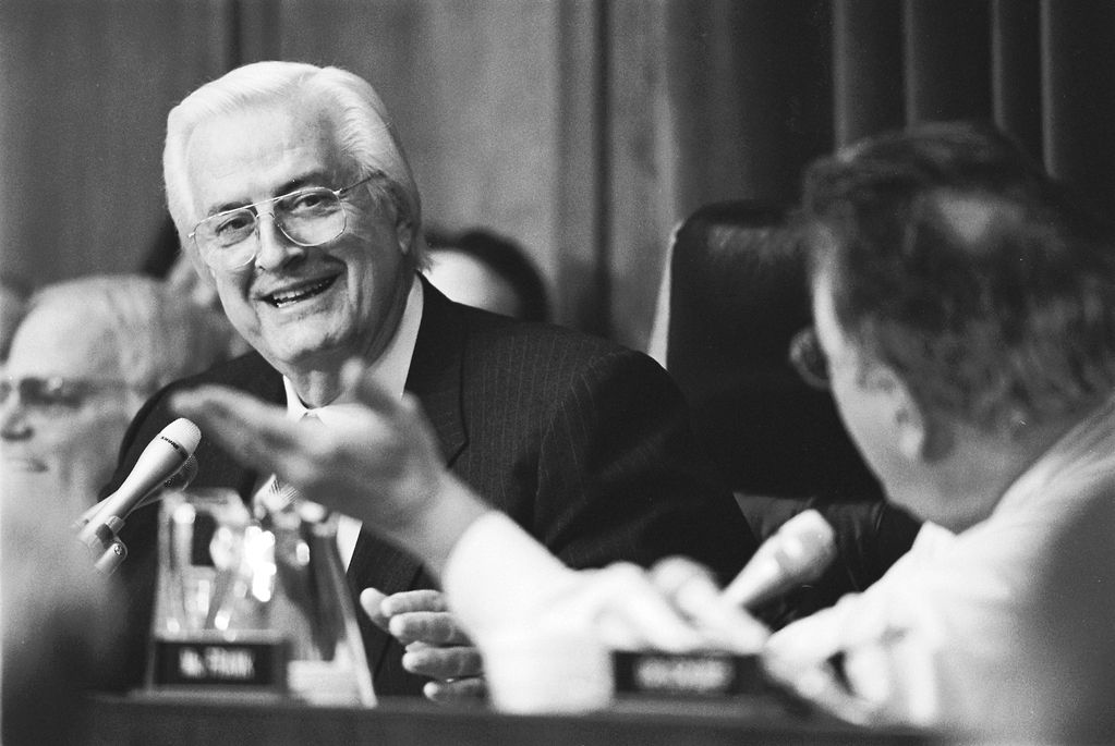 Two men engaged in a conversation during a formal meeting.