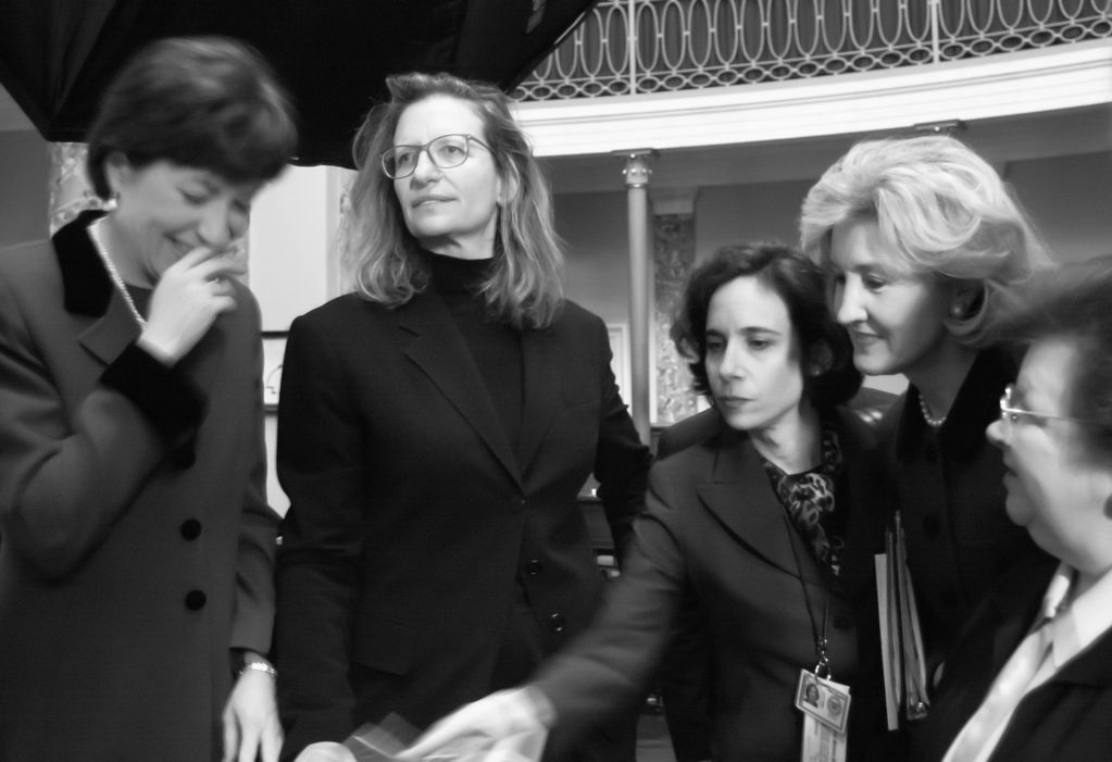 Group of five professional women engaged in conversation.