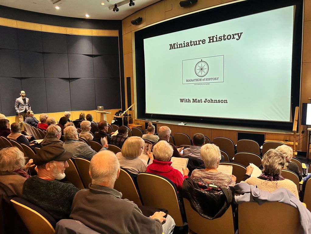 Audience attending a "Miniature History" lecture by Mat Johnson in a theater.