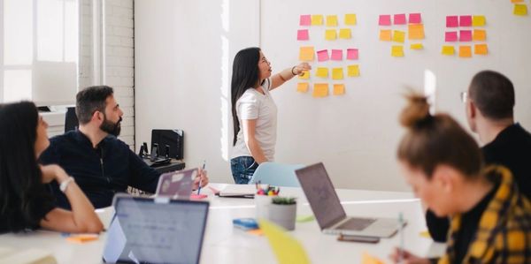 woman gesturing to colored post-its on the wall