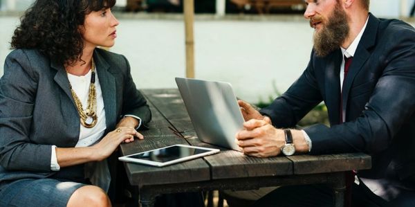 man and woman having a discussion with laptop and tablet