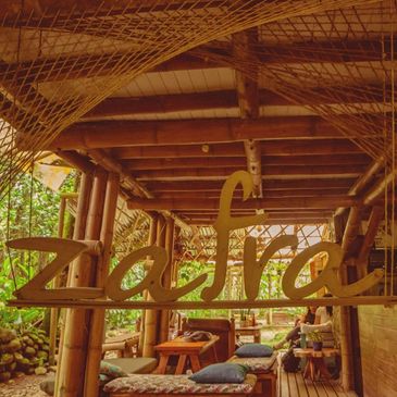 Cozy bamboo seating area with a 'zafra' sign in a tropical setting.