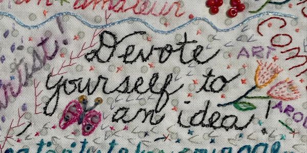 Embroidered phrase with decorative elements on fabric.