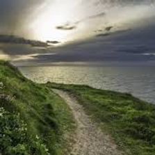 walking path with view of placid ocean and dark skies