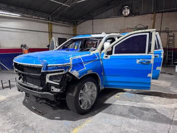 Blue SUV with front-end damage in a repair shop.