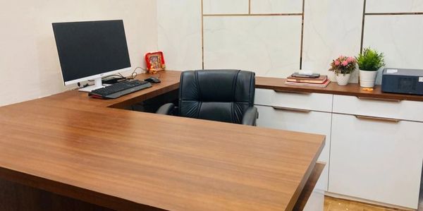 Modern office desk with computer and leather chair.