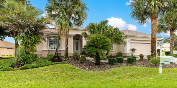 Single-story house with tropical landscaping and palm trees.