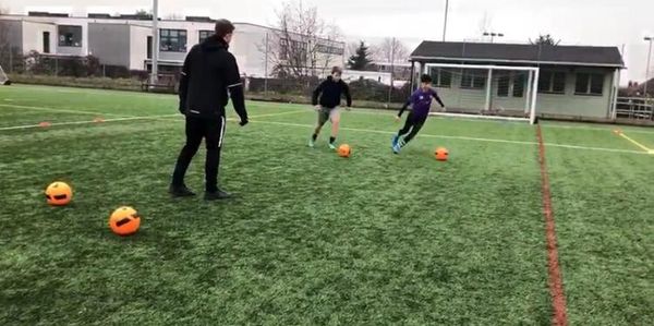 Children playing soccer on a field with a coach.