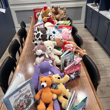 A long table filled with various stuffed animals and children's books.