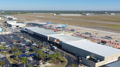 Aerial view of an airport terminal with parked planes and vehicles.