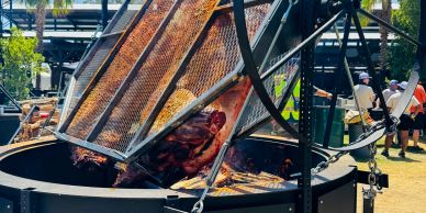 Large outdoor grill with rotating spit cooking meat.