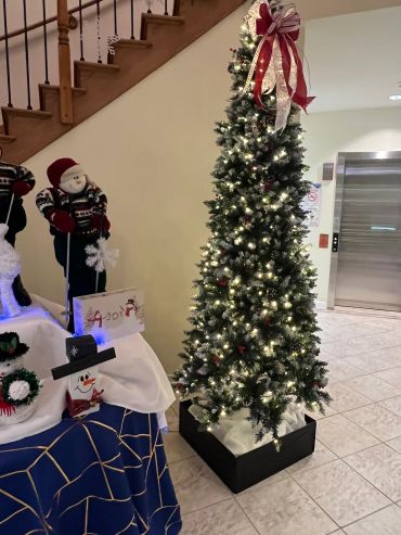 Decorated Christmas tree with lights and festive snowman figures nearby.