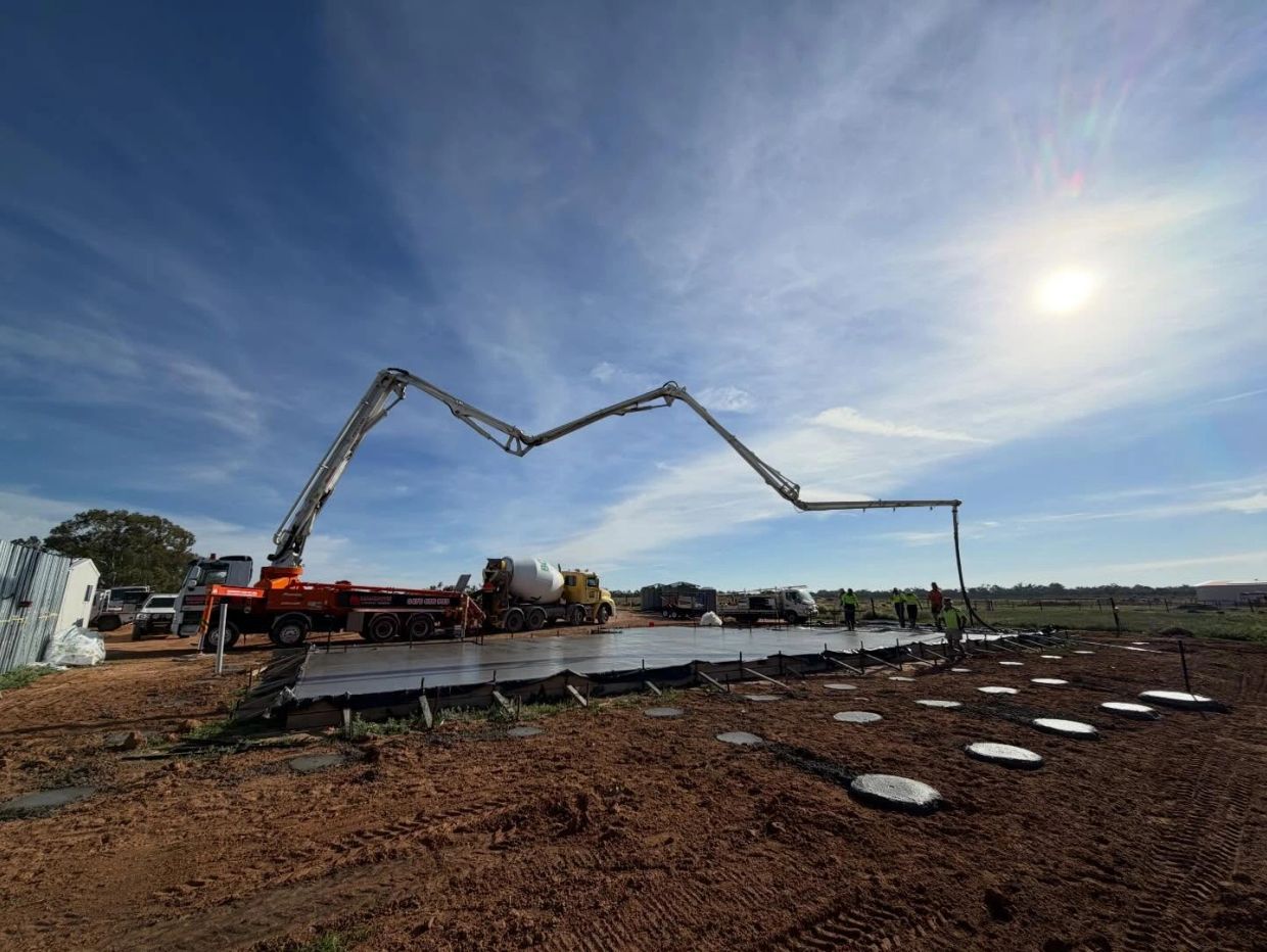 Concrete pouring at a construction site under a clear sky.