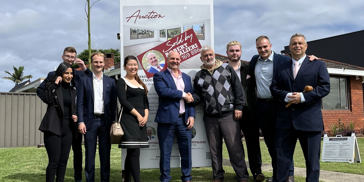 Group of people celebrating a property auction sale outdoors.