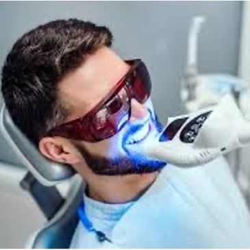 Man undergoing a blue light dental treatment while wearing protective glasses.