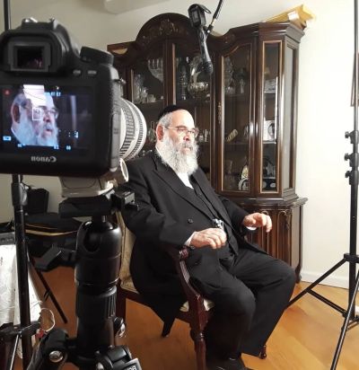 Elderly man being filmed in a home setting with professional camera.