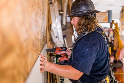 Construction worker drilling into a wooden board.