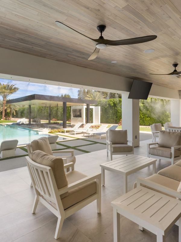 Modern outdoor seating area with pool view and ceiling fans.