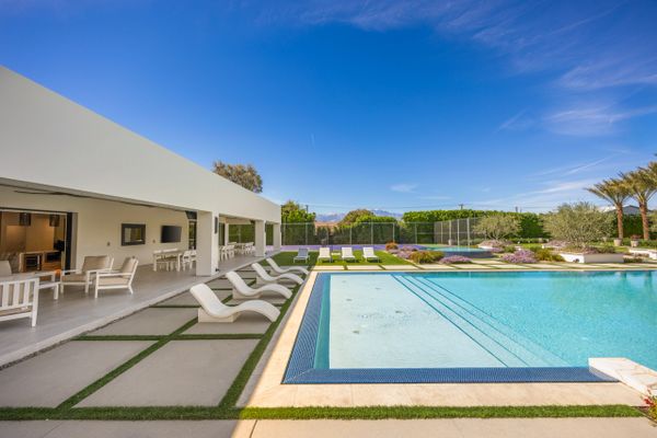 Modern outdoor pool area with lounge chairs and a covered patio.