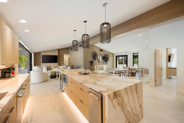 Modern kitchen with marble island and open living space.