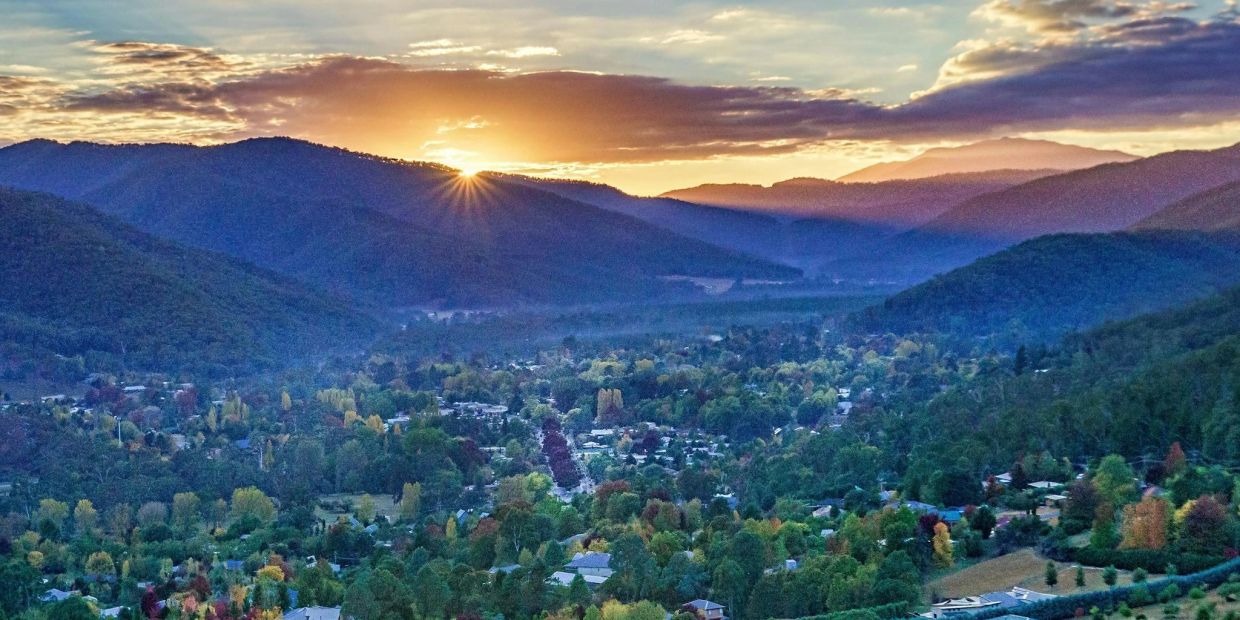 Sunset over a valley town surrounded by mountains.
