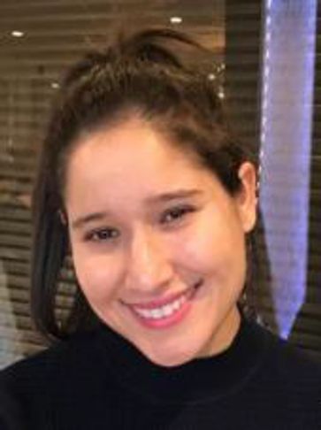 A young woman smiling warmly with a casual hairstyle.