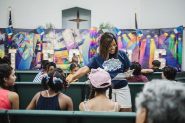 Woman engaging with children in a church setting.