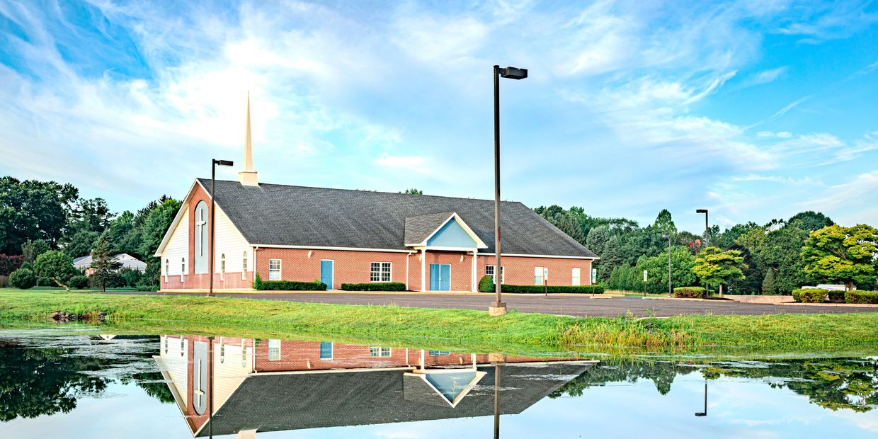 Church building reflected in a pond on a clear day.