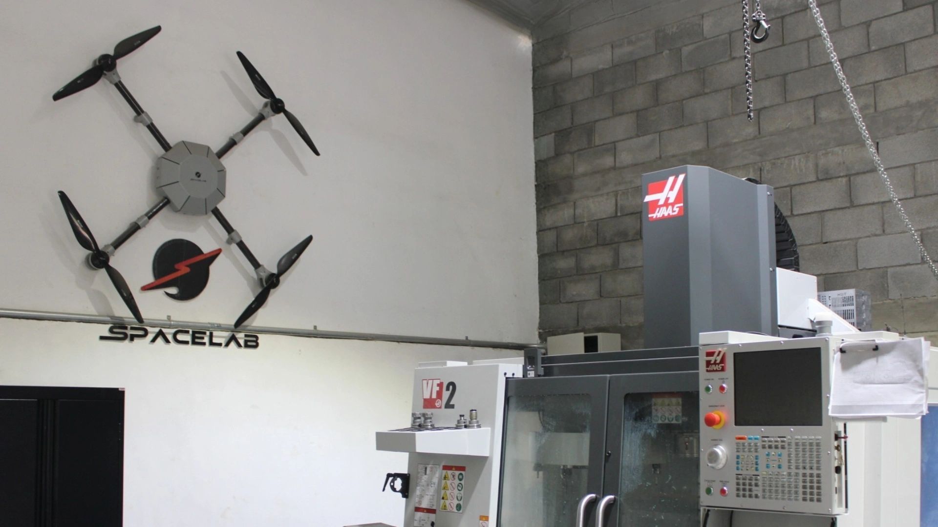 Drone y máquina herramienta en espacio industrial.