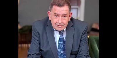 Man in a suit sitting indoors.