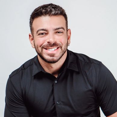Smiling man in a black shirt against a light background.